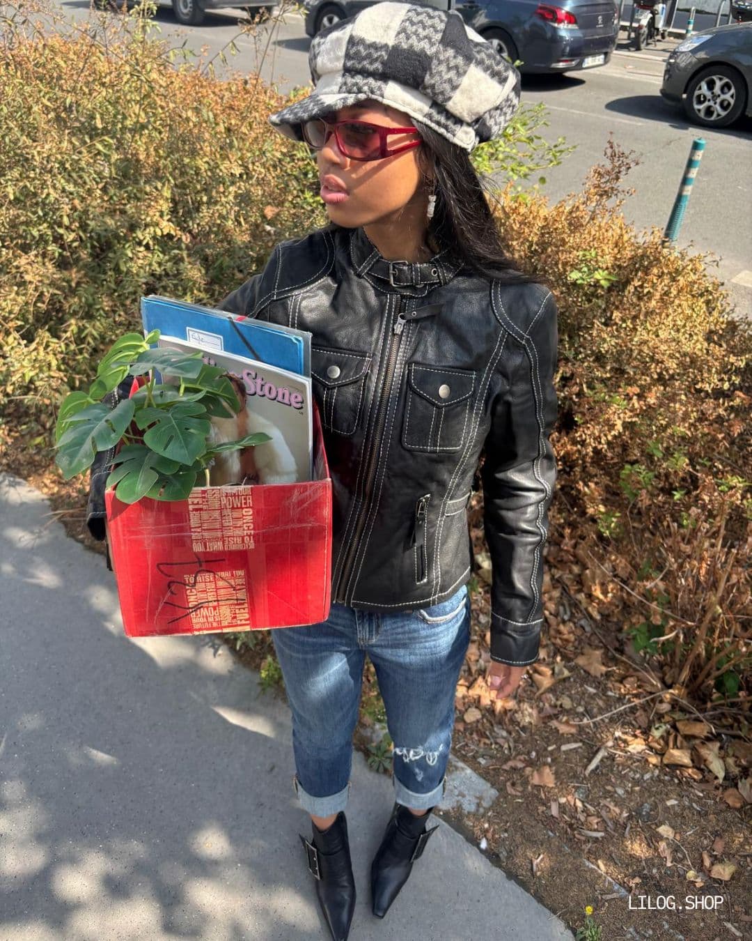 Veste en cuir noir à surpiqûres blanches portée avec un jean et une casquette à carreaux